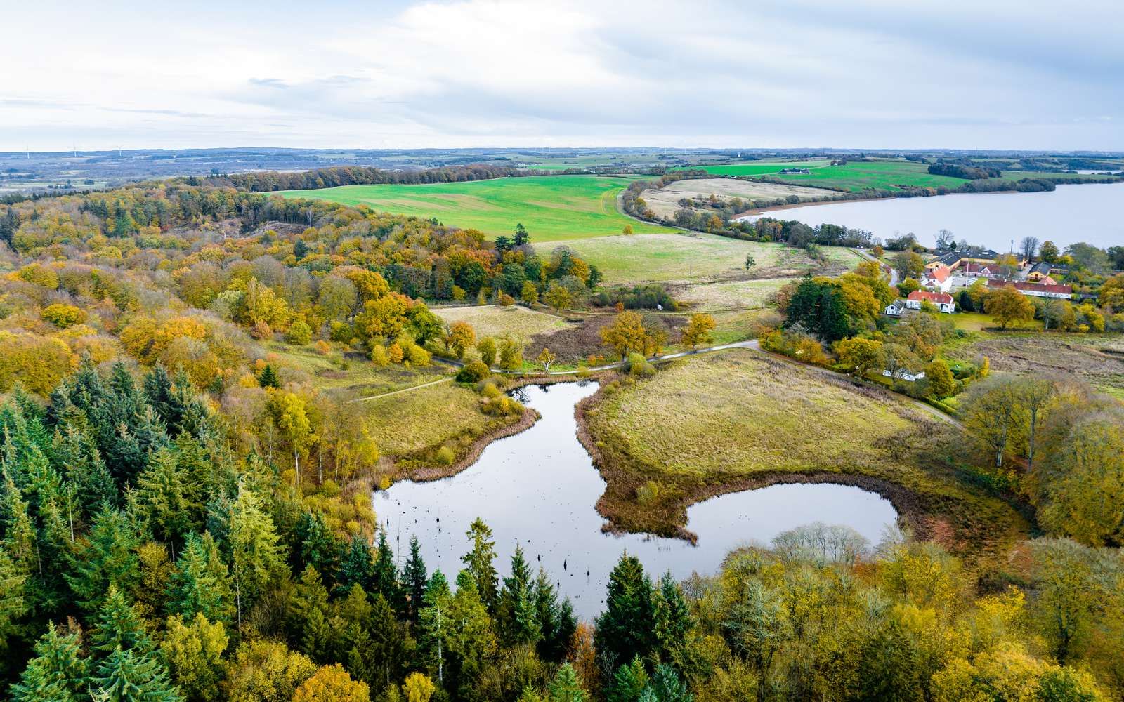Dronefoto ud over Fussingø med herregårdsbygningerne til højre midt i billedet og med Fussing Sø i baggrunden. Søndermade og skoven i forgrunden