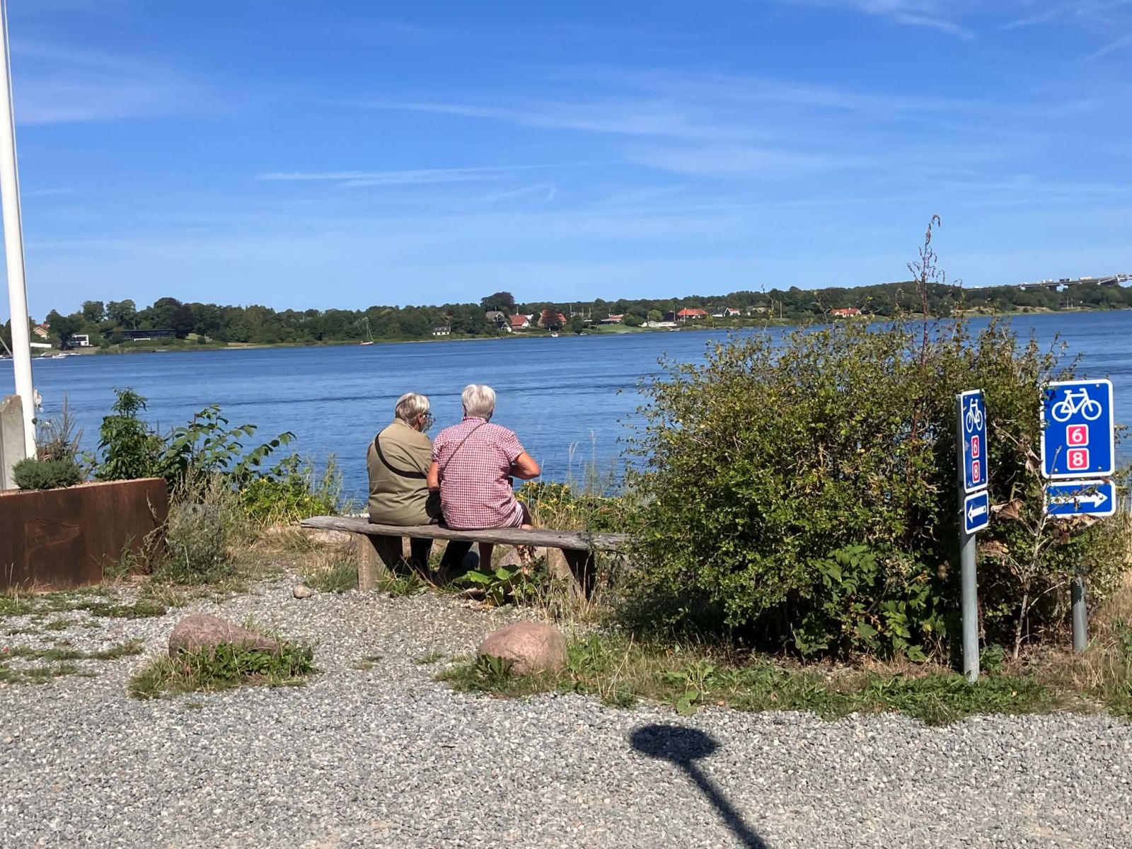 2 damer med ryggen til sidder på en bænk og kigger ud over Lillebælt