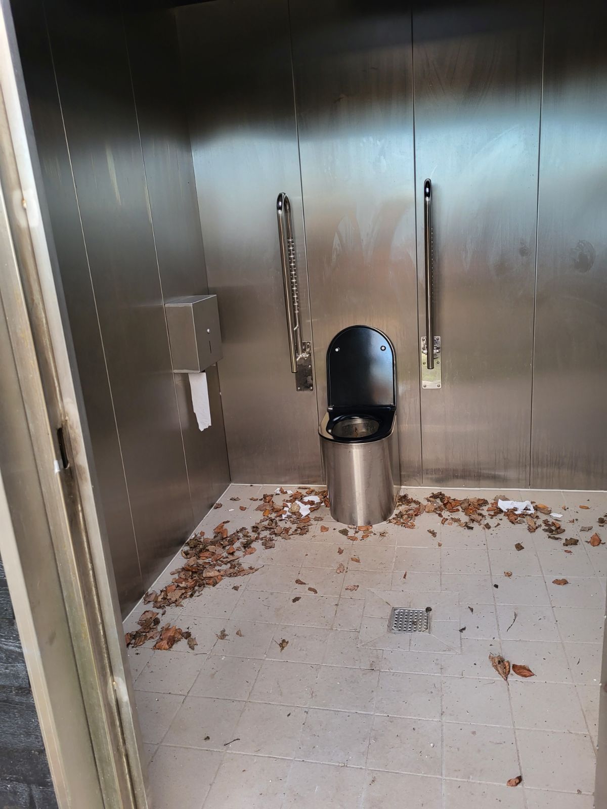 Billede af toilettet indeni med handikap armlæn, der kan slås ned/op