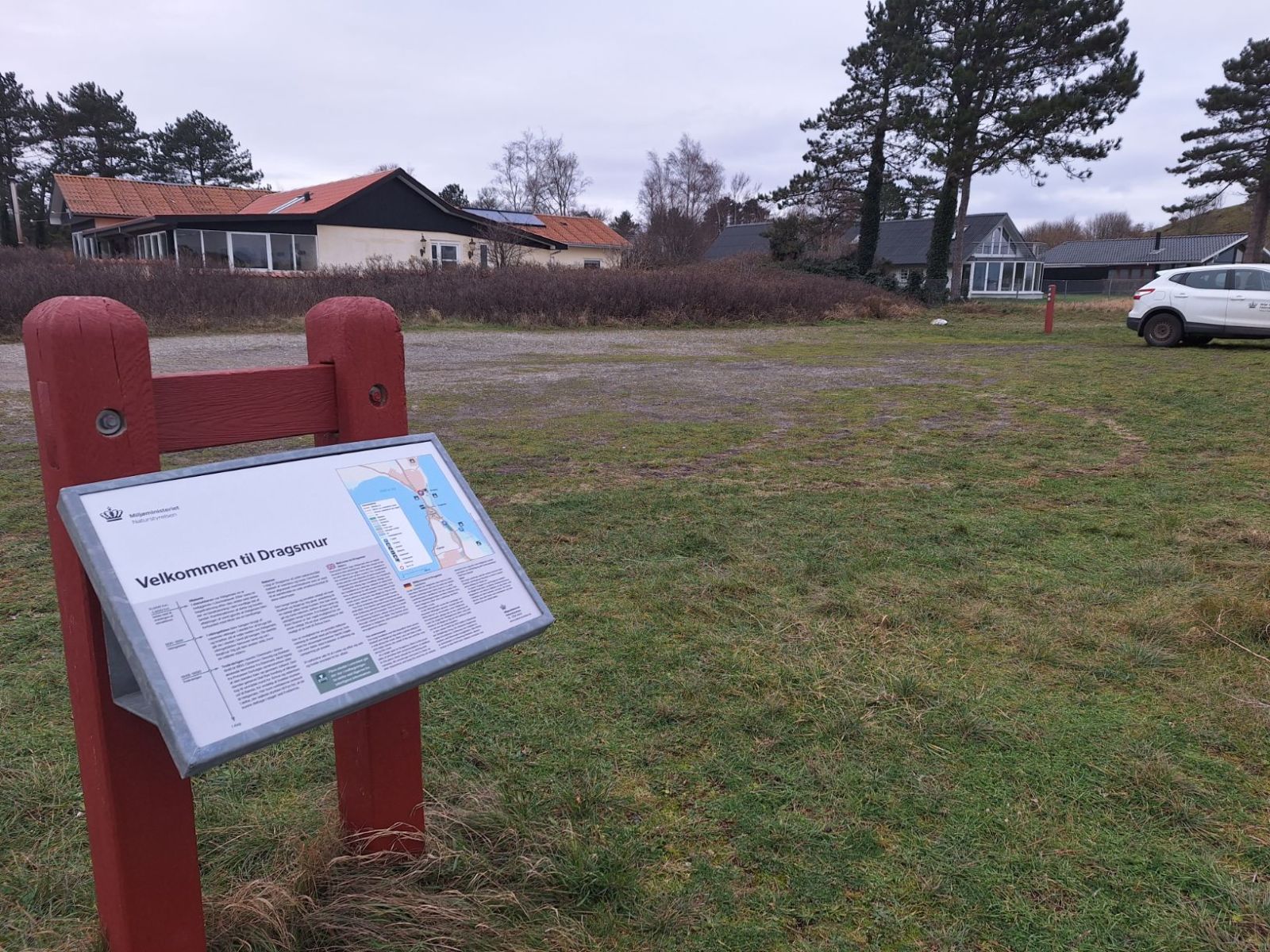Informationstavle for Dragsmur placeret ved parkeringspladsen nærmest vejen.