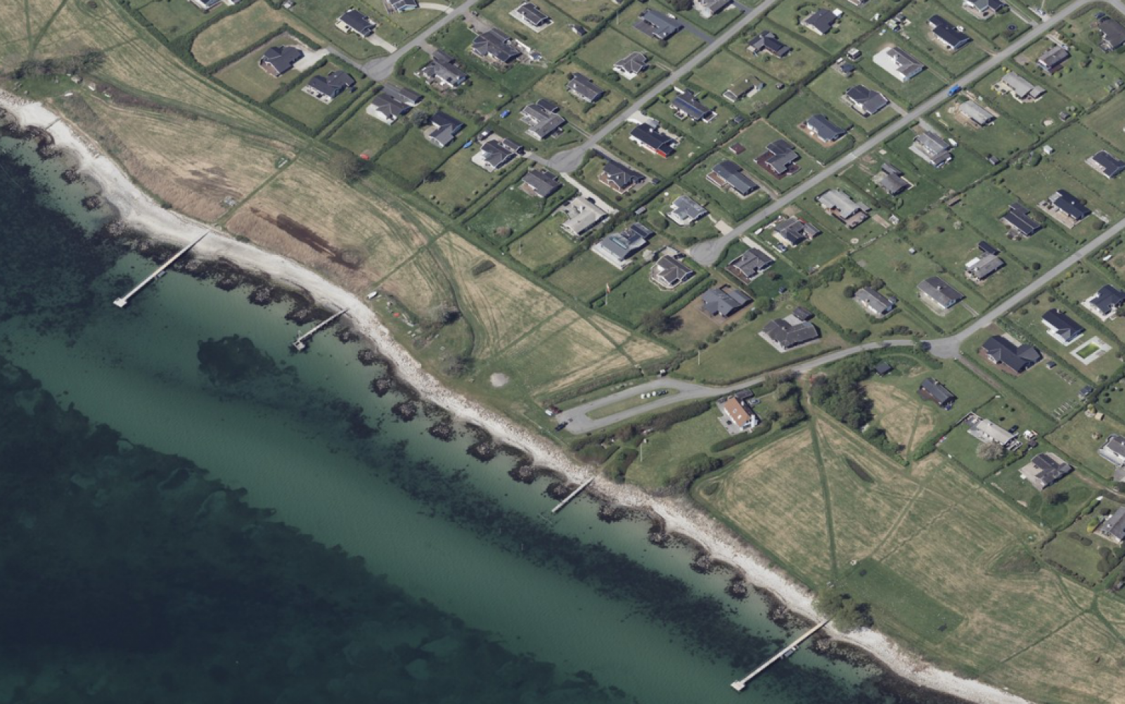 Stranden har store sten ned til vandet