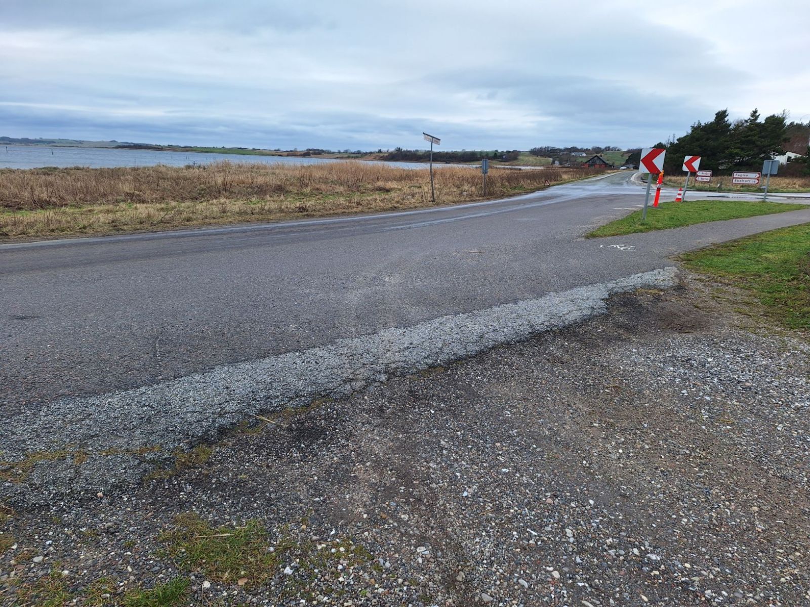 Fra den asfalterede Olaf Ryes Vej er der et let fald i terrænet og en grov overgang til parkeringspladsen som har et underlag bestående af stabilgrus.