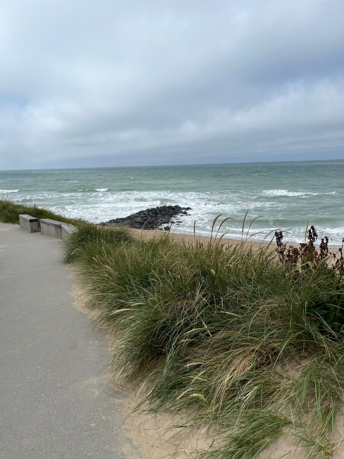 Efter bækslugten vil man gå parallelt med stranden. På venstre side kan man se betonunderlag, man vil komme til at gå på samt siddepladser ud mod havet.