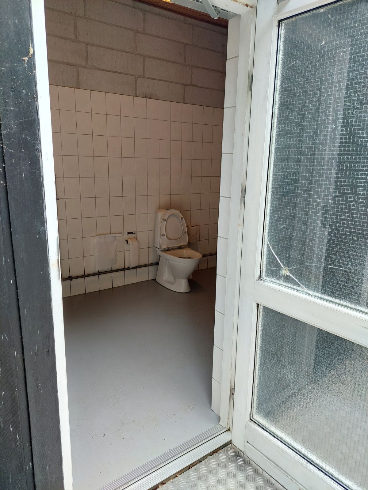 Indgangen til handicaptoilettet sker gennem en dør med matteret glas.