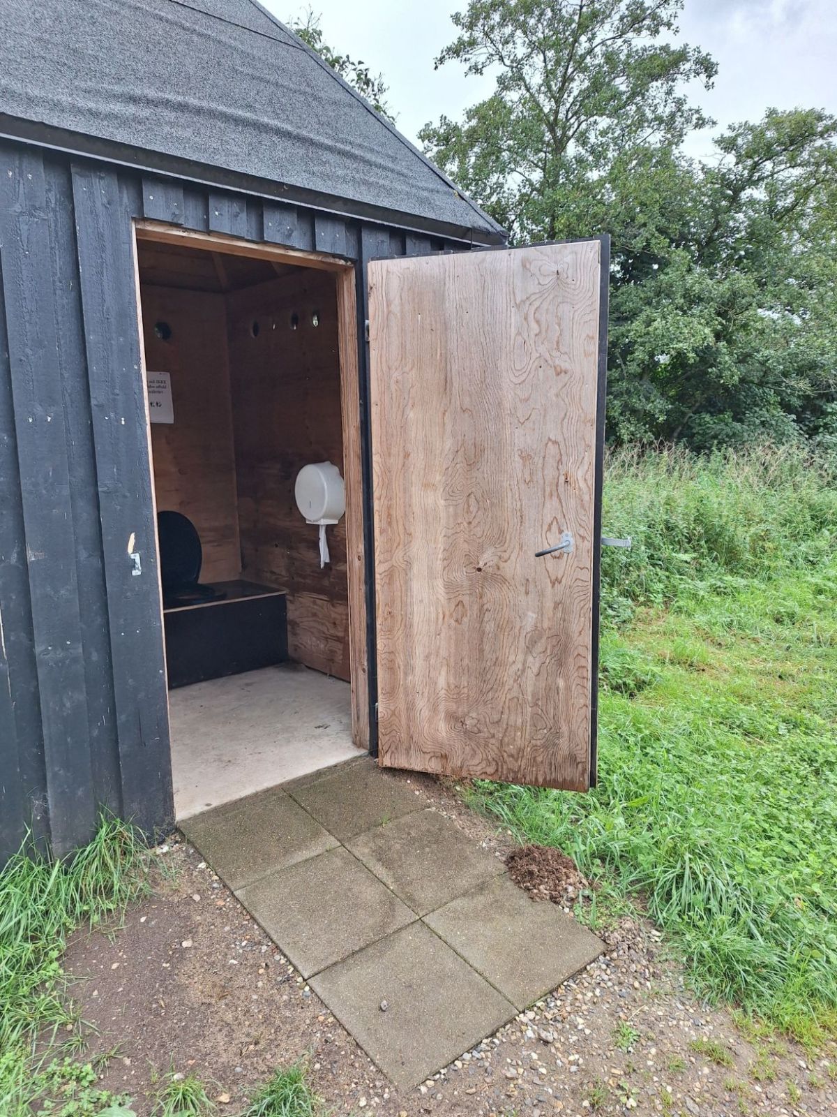 Underlaget til multtoilettet går fra parkeringspladsen med fast stampet grus til 90 centimeter flisebelagt sti over til fast støbegulv. Døren åbner udad og mod højre. 