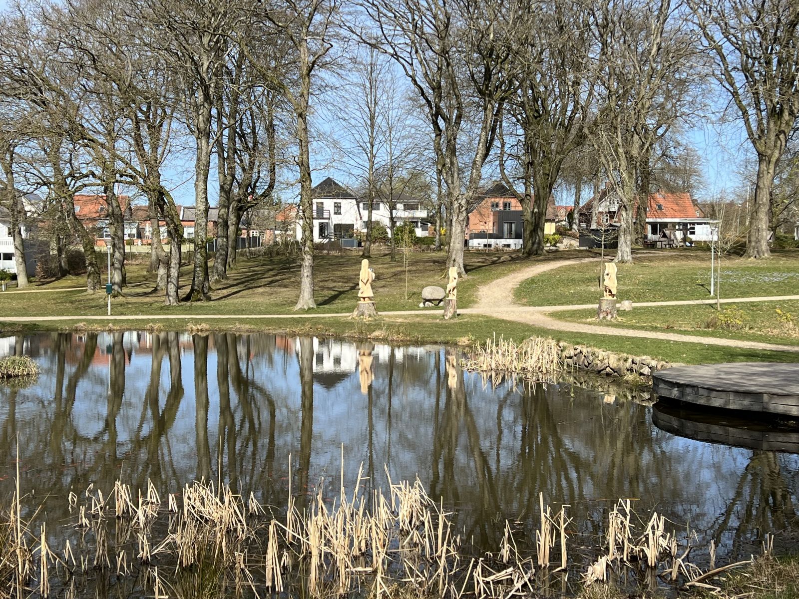 Billede af Brædstrup Parken med søen i forgrunden og stierne i parken. I baggrunden bygninger