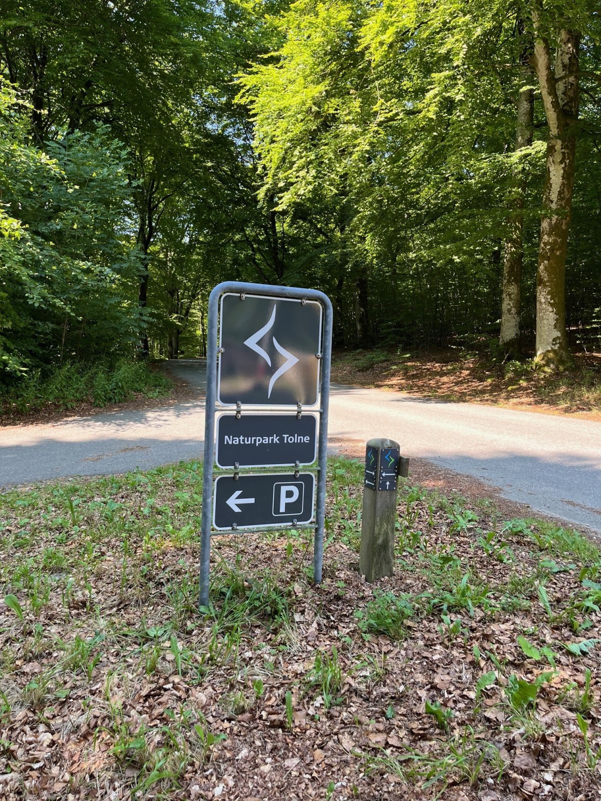 Skiltning Naturpark Tolne og parkering. Pæl med piktogram for ruten. 