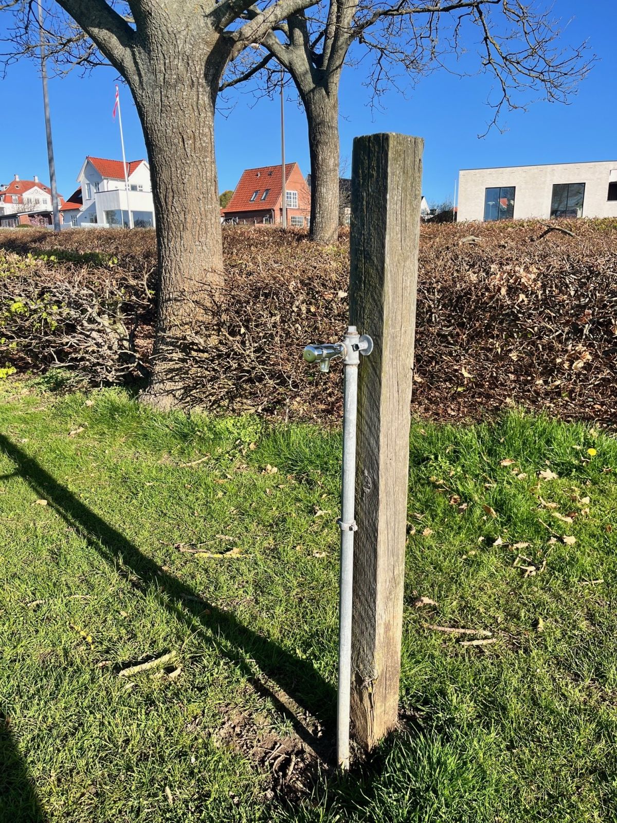Pæl i græsplæne med vandpost med trykknap