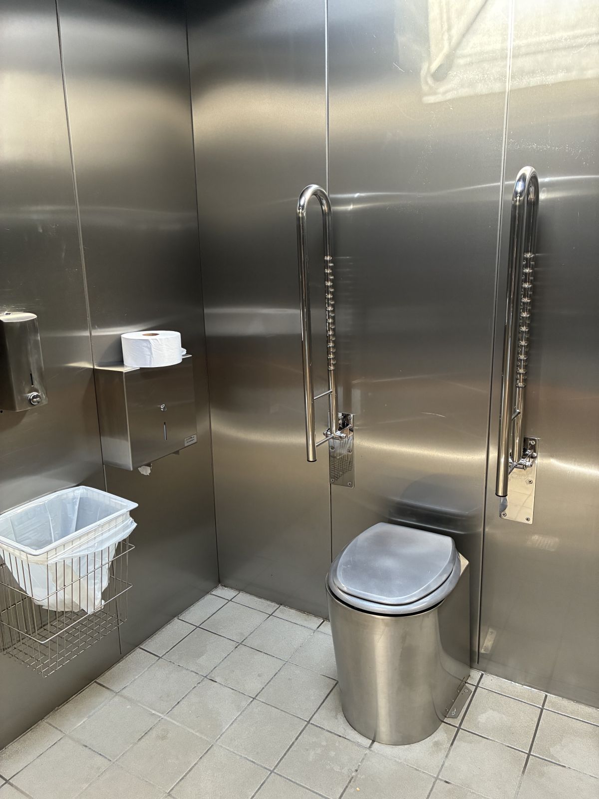 toilettet set inde fra bygningen. Ståltoilet armstøtte til handicappede