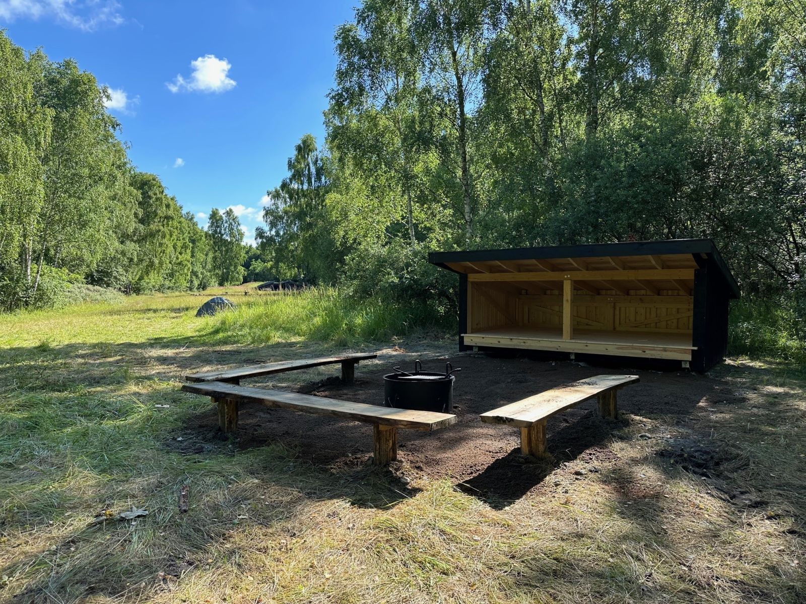 Bålsted med tre bænke omkring. Shelter i baggrunden