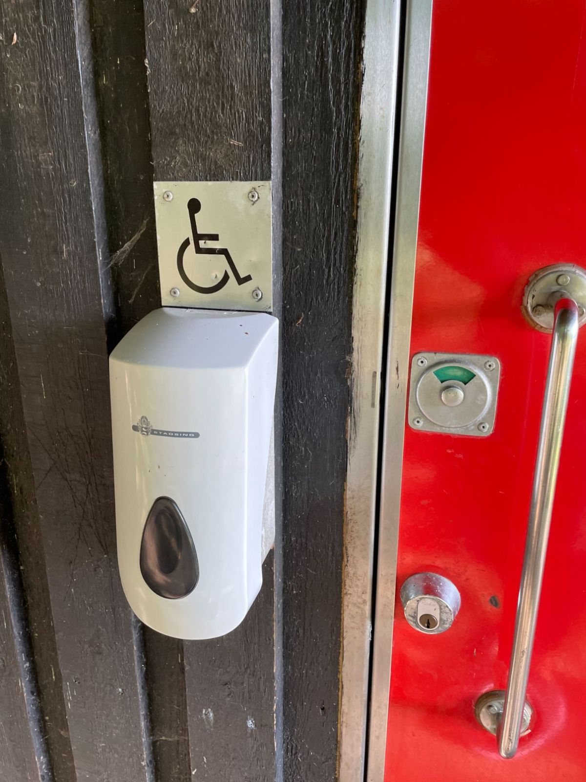 Døren ind til handicaptoilet med håndspritdispenser ved håndtag