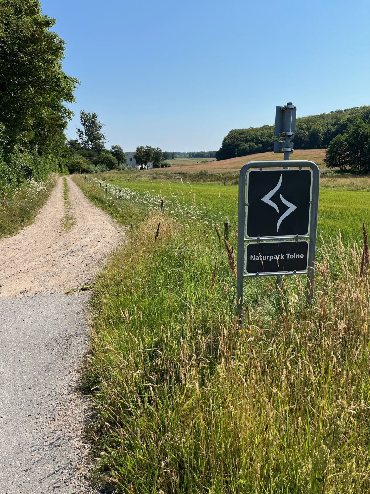 Skiltning for Naturpark Tolne. Underlag er grus.