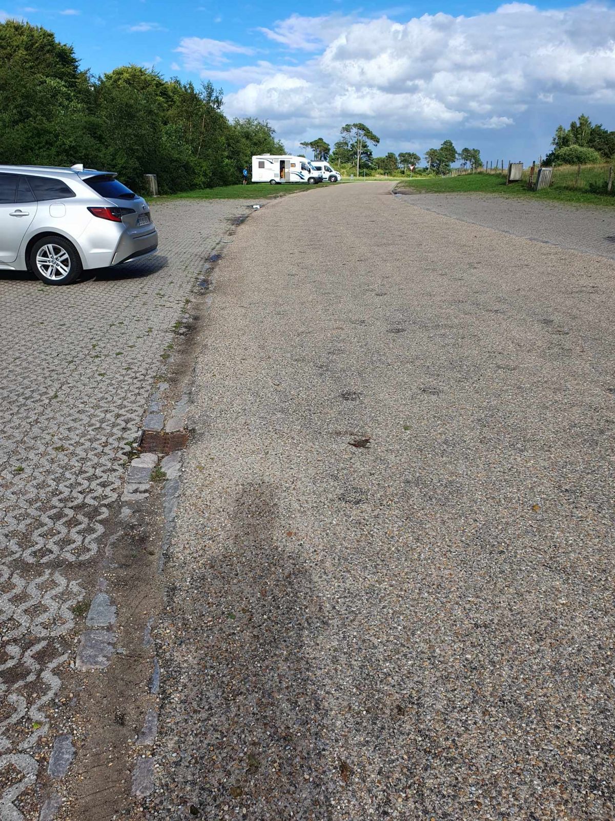 Parkeringspladsens belægning er af asfalt og fliser