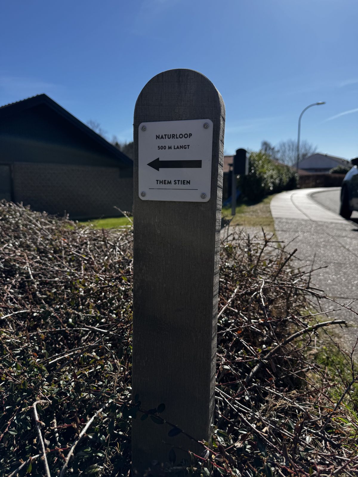 Afmærkningspæl med skilt "Naturloop 500 m langt. Them Stien.
