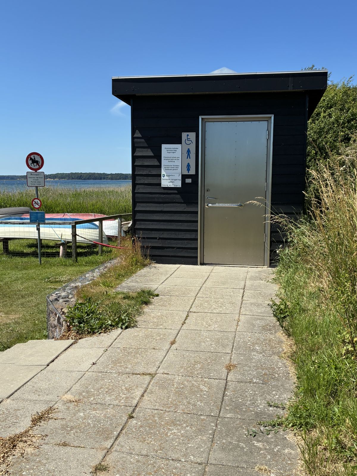 Toiletbygning med flisegang op til.