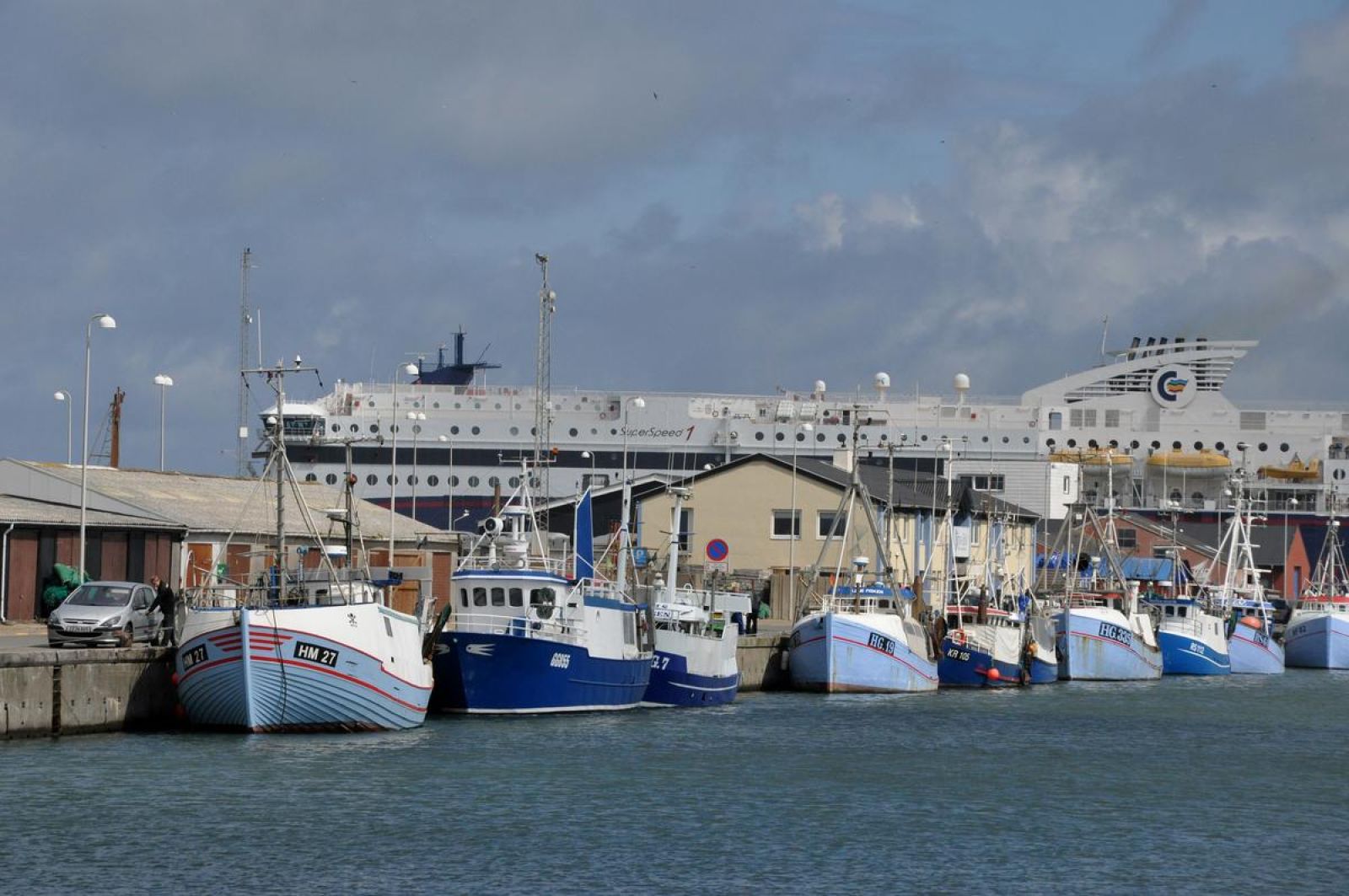 Hirtshals havn og fortøjede både som man kommer til at gå forbi. Underlaget er fortovsfliser og asfalt.