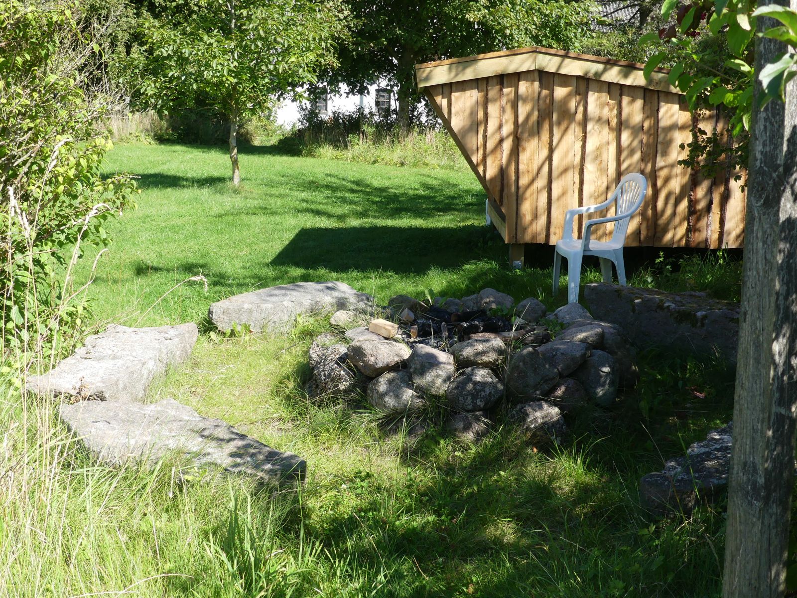 Billede viser sten bålplads med shelteren i baggrunden